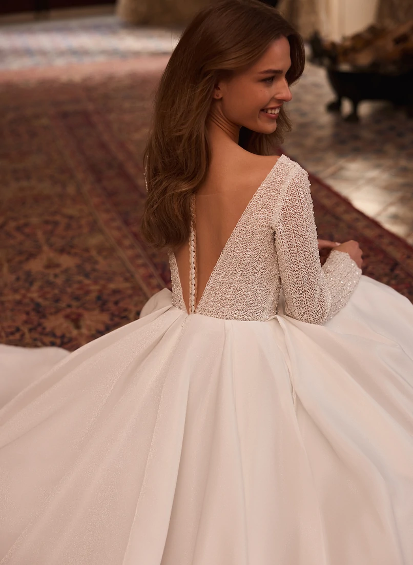 Immagine di una sposa di una sposa girata di spalle, con un abito meraviglioso. sfondo, parete bianca